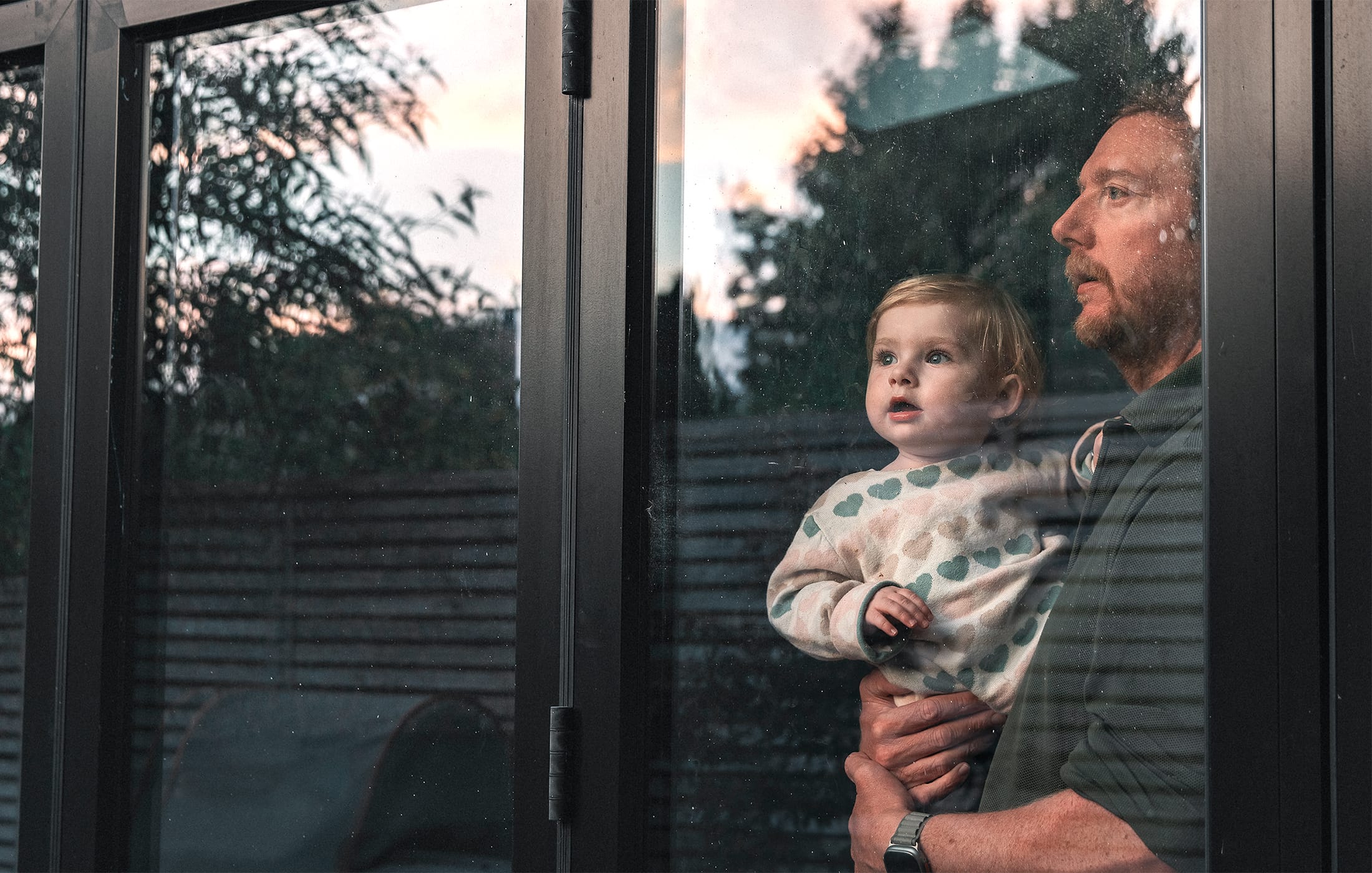 A man holding a child and looking out a window